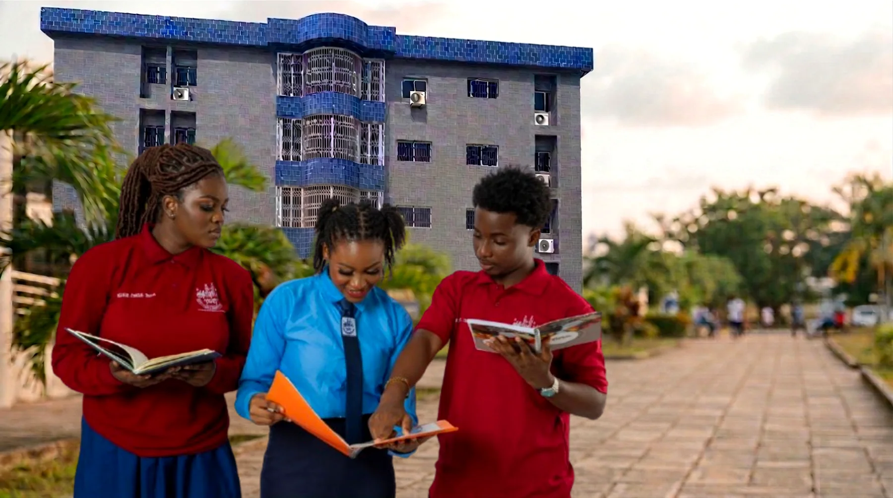 Trois étudiants de l'Université Al Fourqane, en polo et chemise, lisant sur l'allée du campus de Yopougon